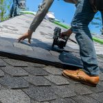 man installing shingles on a roof