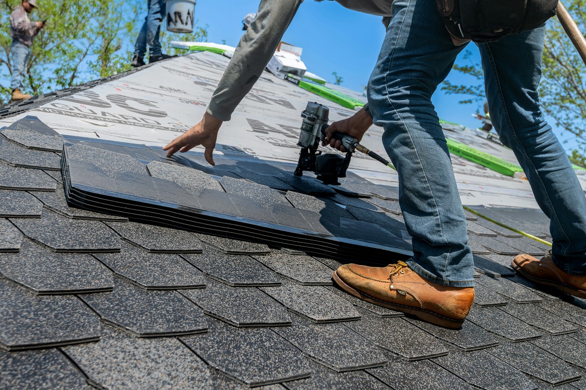 man installing shingles on a roof